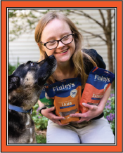 A woman with Down Syndrome holding bags of Finley's dog treats with a dog.